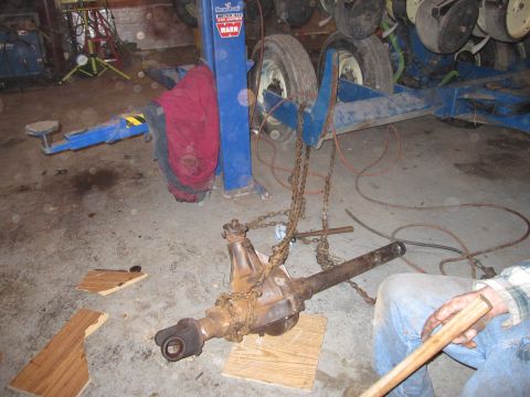 1992 Ford Bronco - A rusty differential axle assembly is being worked on in a garage setting.