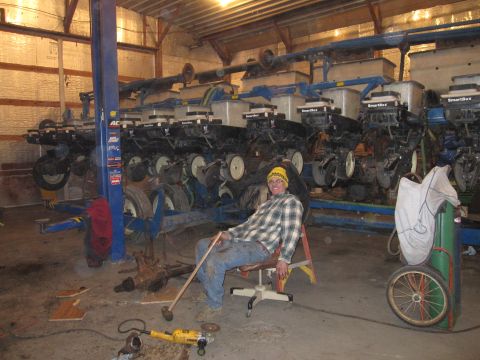 1992 Ford Bronco - A man relaxes in a garage surrounded by agricultural machinery, with tools scattered on the floor.