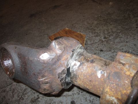 1992 Ford Bronco - Close-up of a rusted metal pipe section showing welds and a piece of wood support.