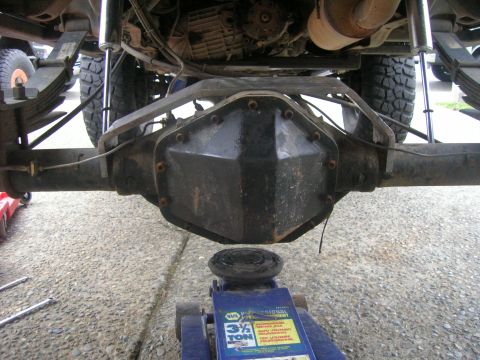 1996 Ford Bronco - View from under the rear of a lifted 4x4 looking forward at the solid rear axle, showing the differential cover, axle tubes, leaf springs a…