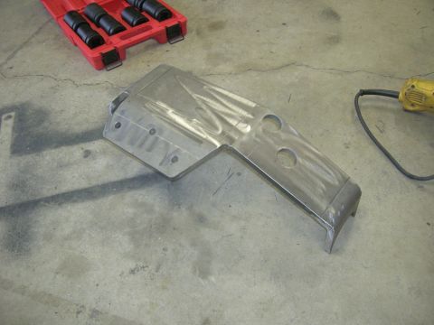 1996 Ford Bronco - A metal skid plate sits on a concrete floor next to a socket set and a power tool.