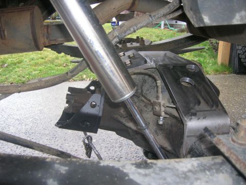 1996 Ford Bronco - Underbody close-up of a leaf-sprung solid rear axle with a chrome-bodied shock absorber running down to a newly fabricated bare-steel shock…