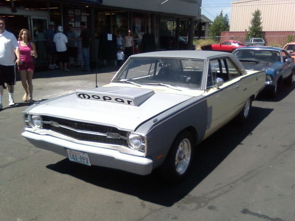 White and gray vintage Mopar coupe with MOPAR hood scoop at an outdoor car show