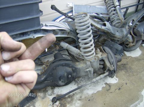 1990 Ford Bronco - Various vehicle suspension components are piled together, with a hand in the foreground.
