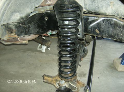 1990 Ford Bronco - Close-up view of a vehicle's front suspension system, highlighting a large coil spring and associated chassis parts.