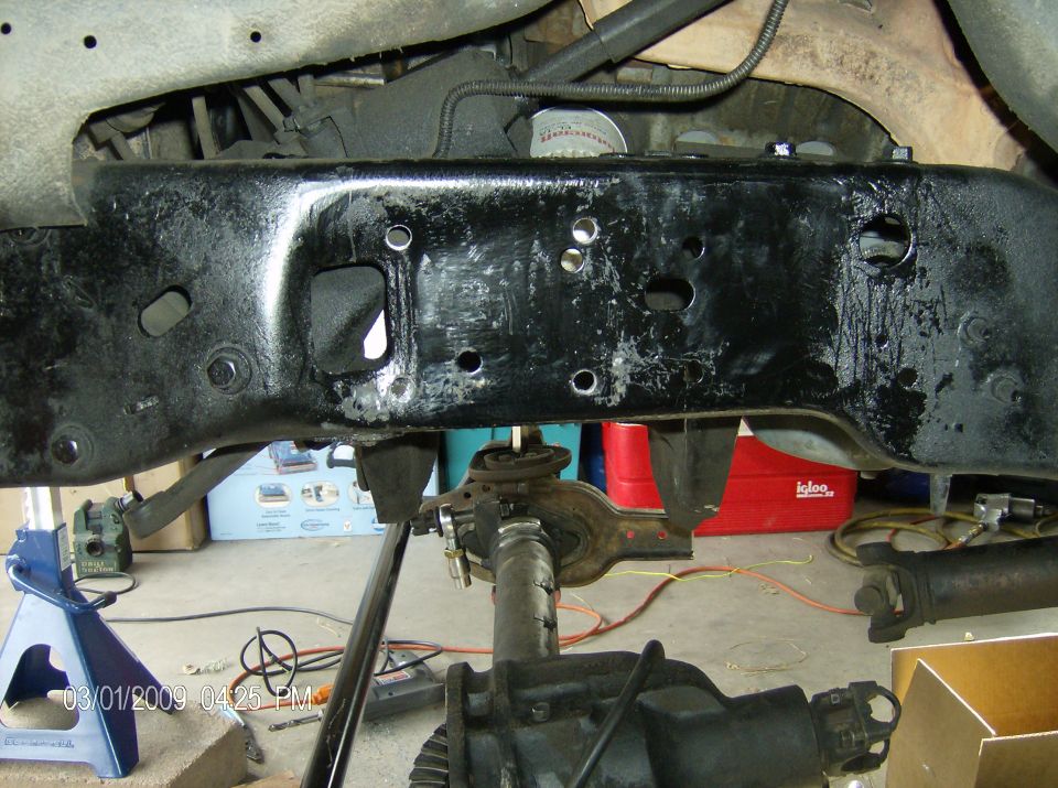 close-up of vehicle frame and suspension parts, jack stands visible