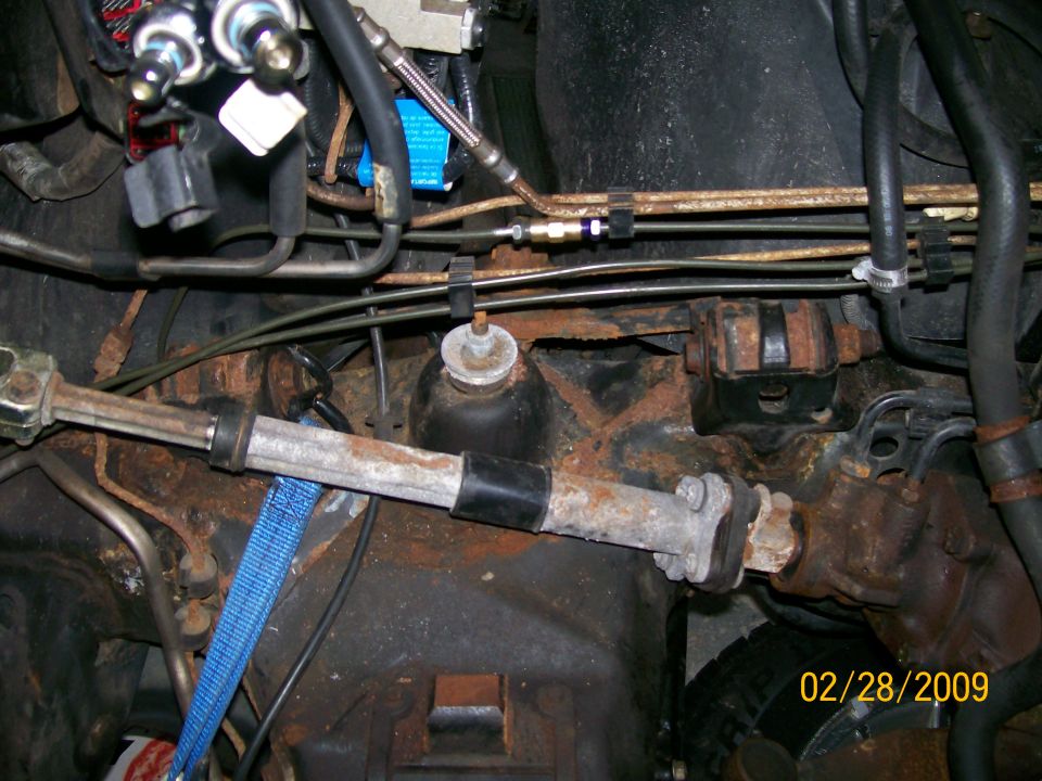 Close-up of rusty steering rack and hydraulic lines under a vehicle