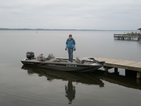 1998 Chevrolet Silverado 1500 - A person stands on a Bass Tracker boat docked next to a wooden pier on a calm body of water.