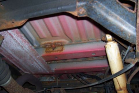 1995 Ford Bronco - Underside view of a vehicle frame with visible rust and a shock absorber.