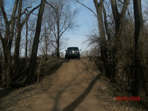 1996 Ford Bronco - A black SUV ascends a dirt path surrounded by trees, with a date watermark visible in the lower right corner.