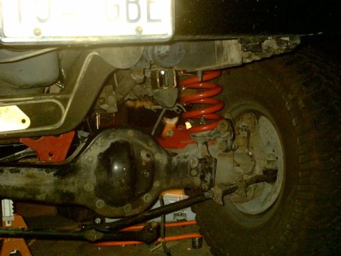 1995 Ford Bronco - Close-up view of a vehicle's rear axle and suspension system, including a red coil spring.
