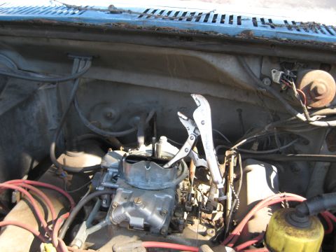 1986 Ford C-350 (Centurion Conversions) - Close-up of a vehicle's engine bay, focusing on the carburetor and a tool.