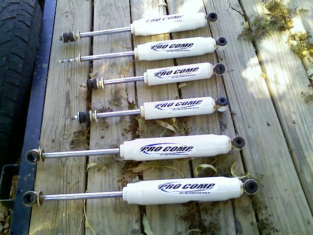 Six Pro Comp shock absorbers laid out on wooden planks