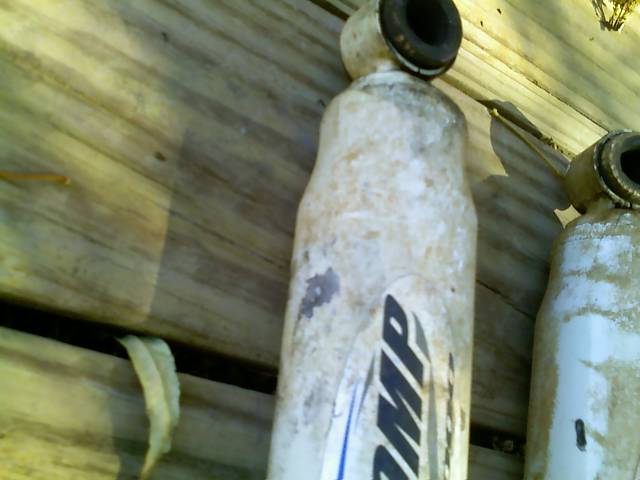 Two shock absorbers with 'AMP' logo visible on one, resting on wooden planks