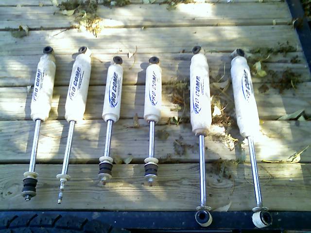 Six Pro Comp shock absorbers laid out on wooden planks