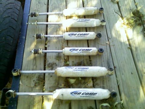 1996 Ford Bronco - Set of six Pro Comp shock absorbers shown on a wooden deck, with a tire visible on the left.