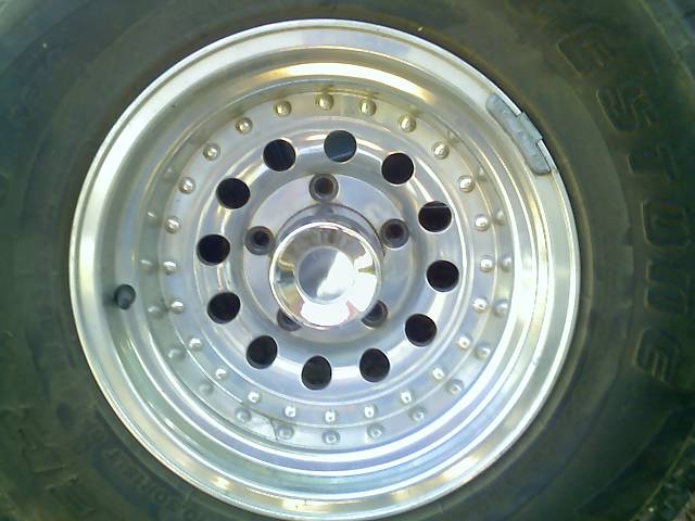 close-up of a shiny alloy wheel with black lug nut holes and a chrome center cap, mounted on a tire