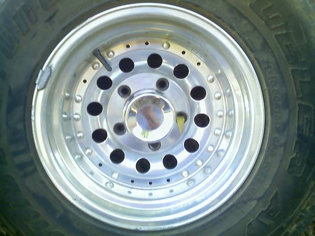 Aluminum alloy wheel with black lug nut holes and a chrome center cap, attached to a tire