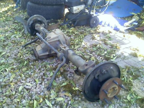 1996 Ford Bronco - A rear axle assembly is shown on the ground, surrounded by fallen leaves and gravel.
