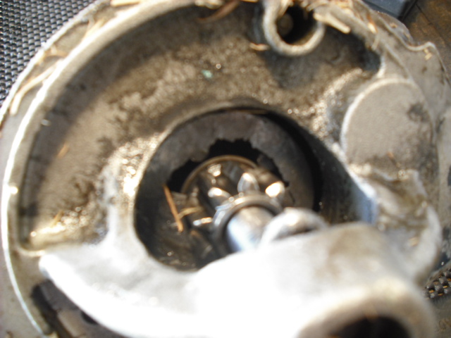 Blurry close-up of a greasy metal housing interior with splined bore and small shaft, disassembled vehicle part