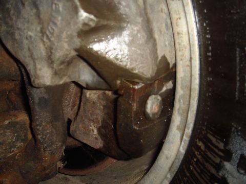 1978 Chevrolet C/K Pickup - Detail of a rusty axle housing and brake components, showing signs of wear and fluid leakage.