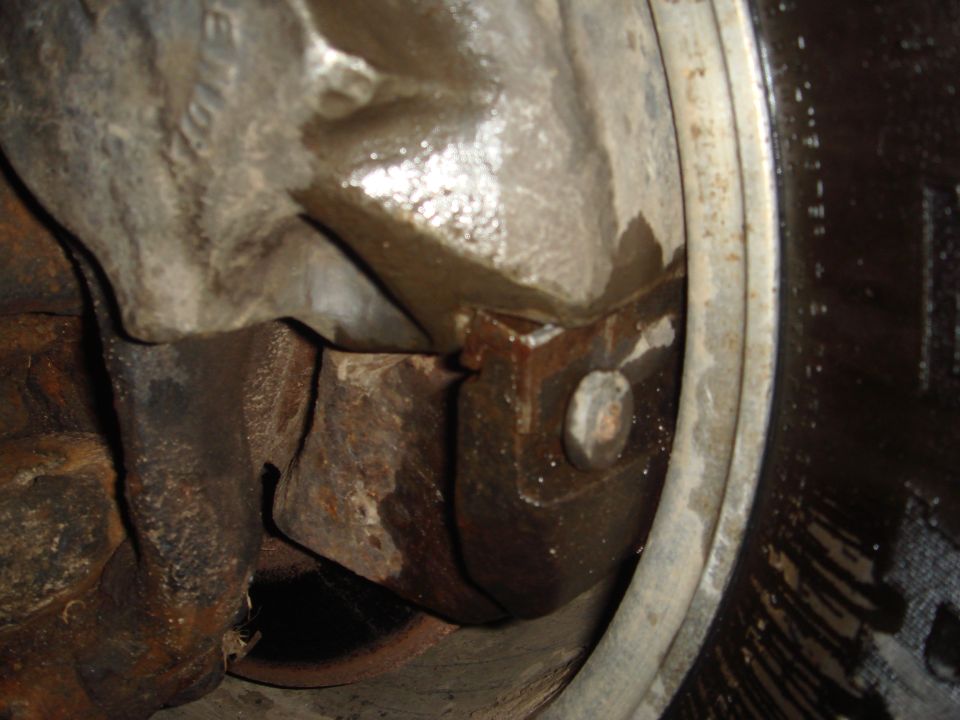 Close-up of rusty axle housing and brake assembly with visible fluid leaks