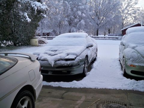 1995 Ford Probe - Cars sit parked in a driveway, blanketed by a fresh snowfall under a winter sky.
