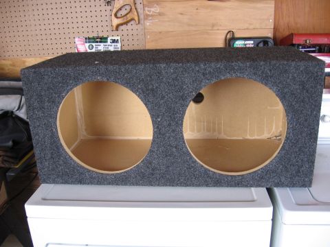 1980 Jeep CJ7 - Carpeted dual subwoofer enclosure with two large circular speaker cutouts.
