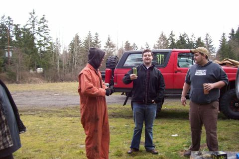 1995 Ford Bronco - A red SUV with a spare tire on the back is parked outdoors with three people standing nearby.