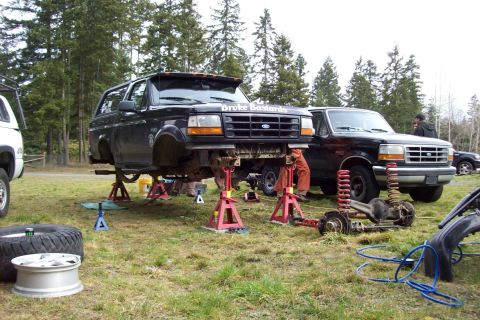 1995 Ford Bronco - Two Ford Broncos are shown outdoors, one undergoing front-end repair work.