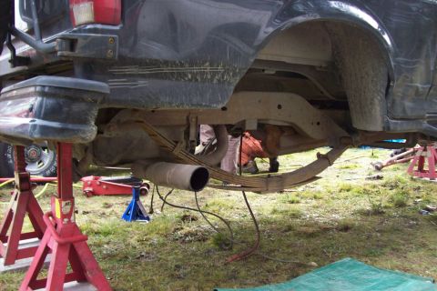 1995 Ford Bronco - The underside of a truck is shown, with its rear suspension components exposed and elevated on stands.