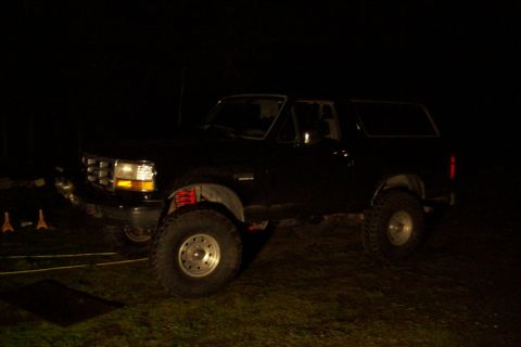 1995 Ford Bronco - A black Ford Bronco with aftermarket suspension and tires is parked outdoors at night.