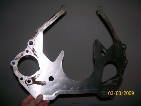 1995 Mercury Grand Marquis - A person's hand holds up a metal automotive part, likely an engine or transmission adapter plate, against a plain gray background. The part…