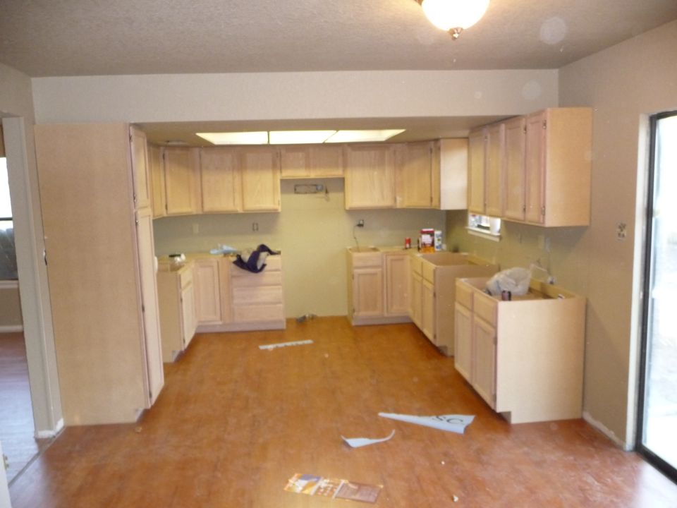 Kitchen under renovation with light wood cabinets and light brown flooring.