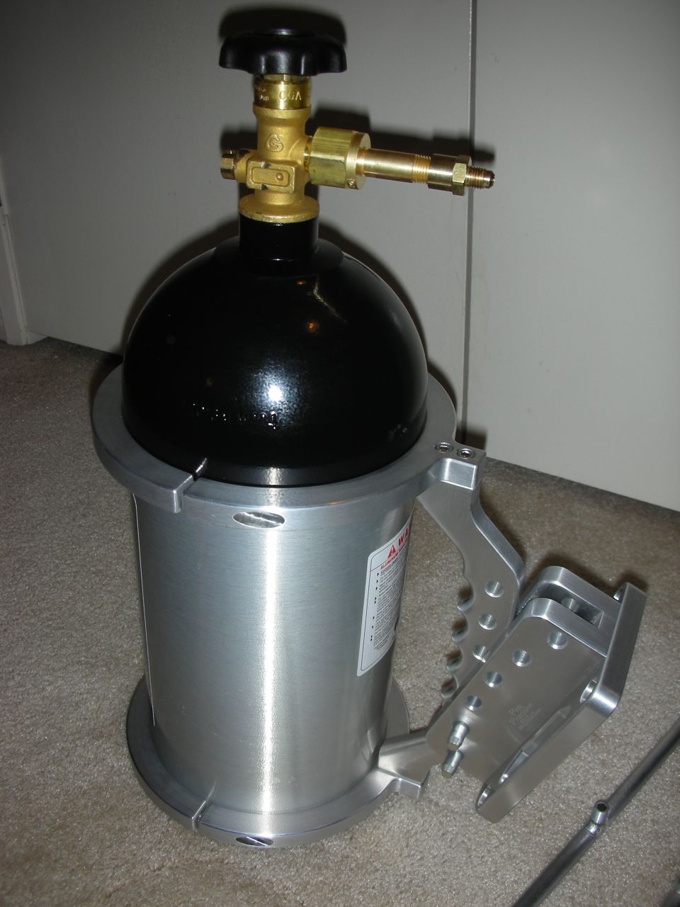 Black compressed gas cylinder with brass valve and silver aluminum housing with handle.