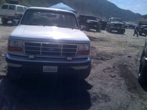 1979 Ford Bronco - A white Ford pickup truck is parked in a dirt lot with several other off-road vehicles and a blue tent in the background. The truck has a C…