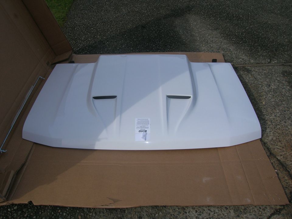 White aftermarket Ford Bronco hood with vents, laid on cardboard.