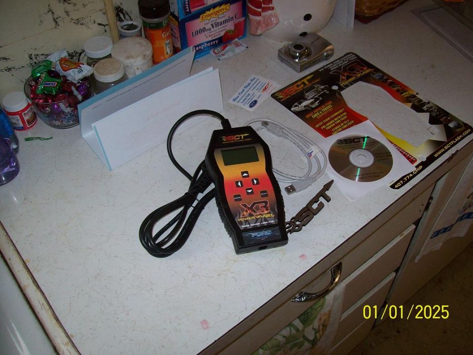 SCT XCal handheld tuner with cable, software CD, and packaging on a counter
