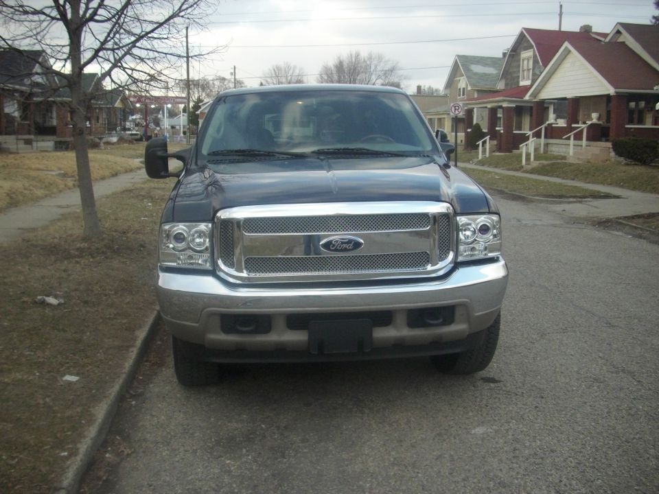 Front view of a dark blue Ford Excursion with chrome grille parked on a residential street