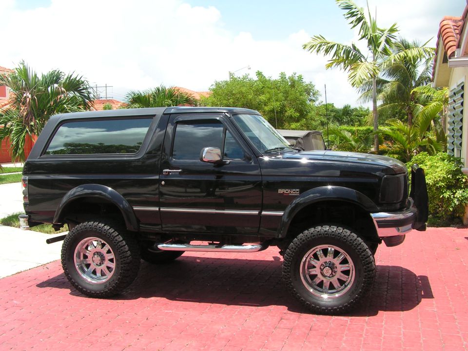 Black 1994 Ford Bronco parked on a red brick driveway.