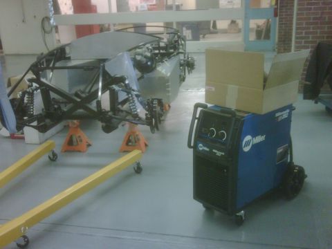 1996 Ford Bronco - Photograph of a tube-frame chassis on stands next to a Miller welder in a shop.