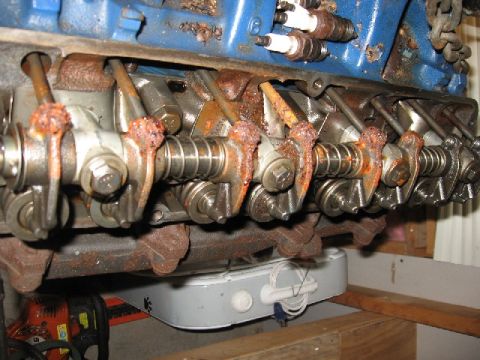 1966 Ford F-100 - Close-up of a removed cast-iron cylinder head sitting upside down, showing the rocker arms, pushrods and valve springs coated in surface ru…