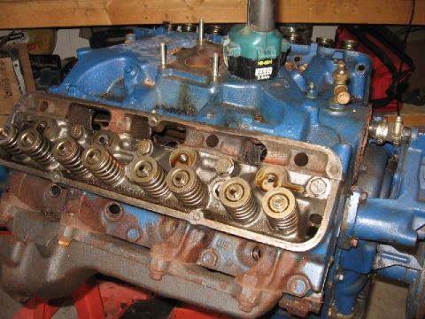 1966 Ford F-100 - A V8 cylinder head sits on top of an engine block during teardown, valve cover off to show the valve springs, retainers and rocker studs wi…