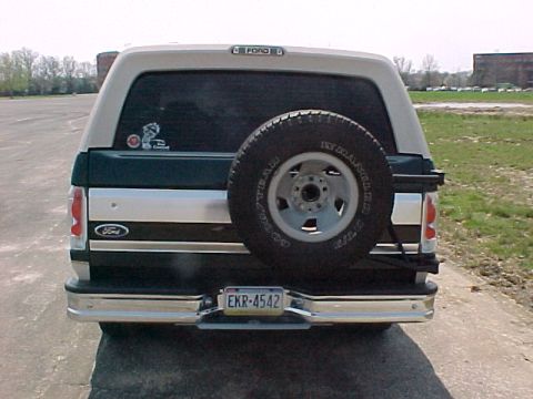 1993 Ford Bronco - The rear of a two-tone Ford Bronco, a spare tire on the tailgate and a chrome bumper.