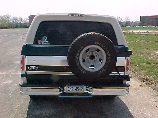 Rear view of green and white Ford Bronco with swing-away spare tire carrier
