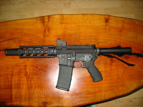 1996 Ford Bronco - A black AR-15 style rifle with a red dot sight and a loaded magazine sits on a wooden table.