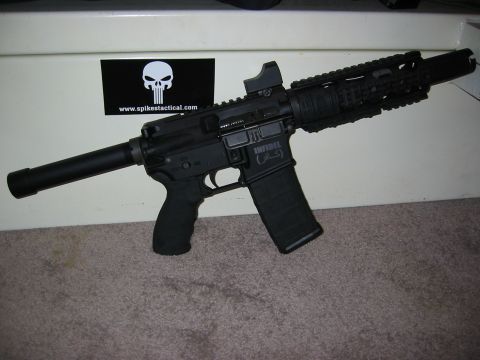 1996 Ford Bronco - A black rifle with a suppressor is displayed on a carpeted floor in front of a white surface with a sticker. The rifle has a magazine inser…
