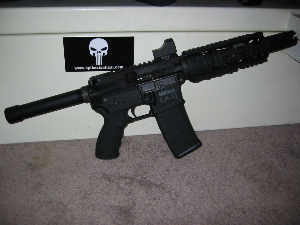 Black rifle with suppressor, magazine, and red dot sight.