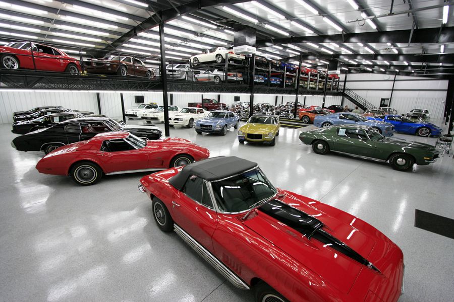 Red 1969 Chevrolet Corvette Stingray convertible with black stripes in a showroom.