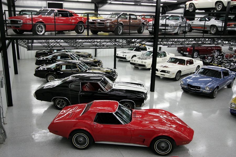 Red 1970s Chevrolet Corvette Stingray in foreground, other classic cars in background.